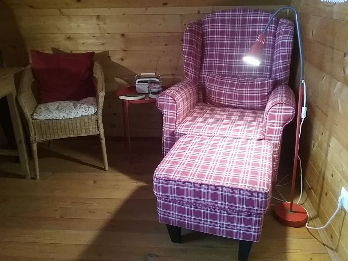 Gemütliche Sitzecke im Ferienhaus mit Ohrensessel vor heller Holzvertäfelung